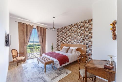 a bedroom with a bed and a table and a window at La Maison du Grand Bossieu in Bossieu