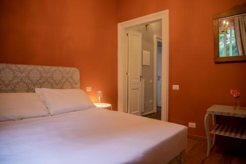 a bedroom with a white bed and an orange wall at Ca Meison in Cannobio