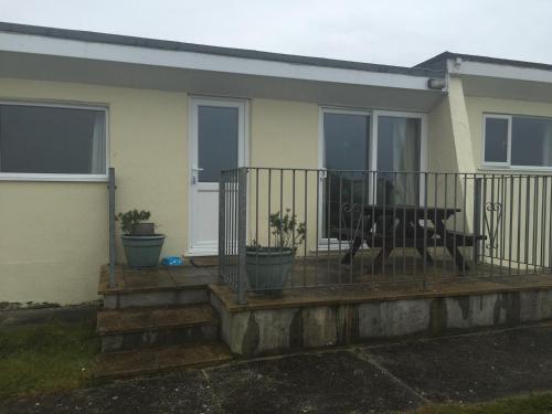 a house with a balcony with a table on it at Widemouth Waves Holiday Chalet in Poundstock