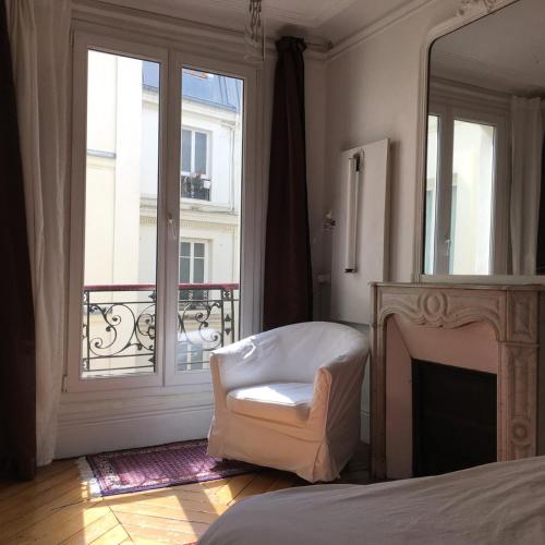 1 dormitorio con cama, silla y espejo en Plein centre, en París