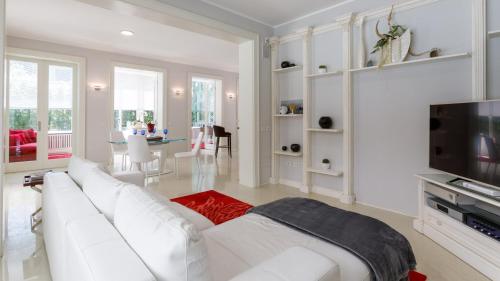 a white living room with a white couch and a tv at Villa Guidi 10 Emma Villas in Milano Marittima