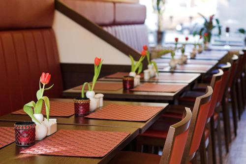 Una fila de mesas con flores en tazas. en Hotel Wiking, en Kiel