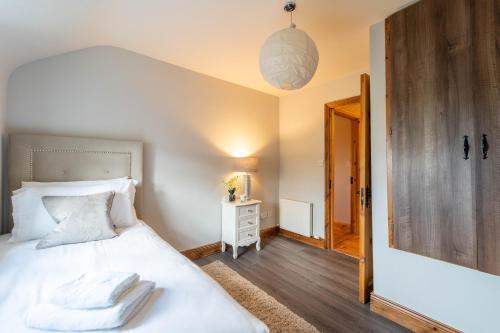 a bedroom with a bed with white sheets and a mirror at Dingle View - 37 Tír Na Fiuise in Dingle