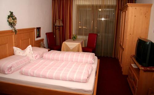um quarto de hotel com duas camas e uma televisão em Hotel Edelweiss em Fügen