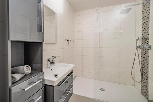 a white bathroom with a sink and a shower at Ostseeblick Apartmenthaus im Ostseebad Nienhagen in Ostseebad Nienhagen