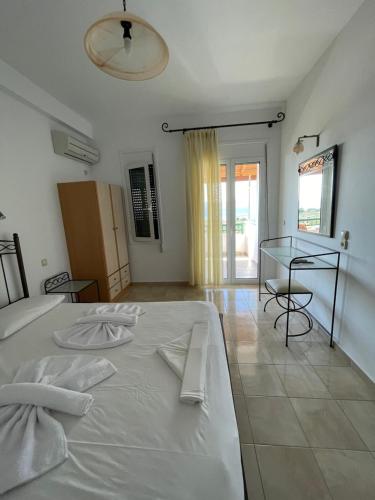 a bedroom with a white bed and a glass table at Niriides Rooms in Elafonisos