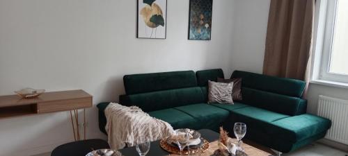 ein Wohnzimmer mit einer grünen Couch und einem Tisch in der Unterkunft Tabago Studio 1 Opole, Kośnego in Oppeln