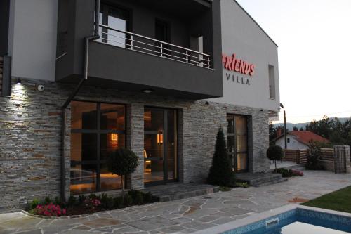 a building with a swimming pool in front of it at Family Hotel Friends Villa in Enchets