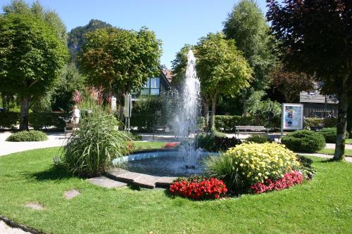 a fountain in the middle of a park with flowers at Pension Salzburger Hof in Fuschl am See