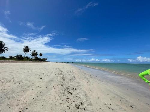 une personne debout sur une plage de sable avec des palmiers dans l'établissement APARTAMENTO EM PEROBA - MARAGOGI, à Maragogi