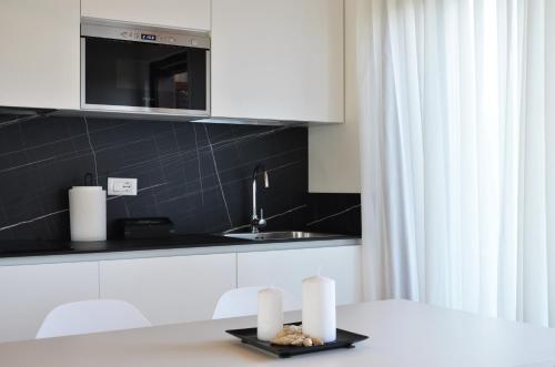 uma cozinha com armários brancos e uma mesa com toalhas de papel em Golf Jesolo Village ➔ Attico con Piscina em Lido di Jesolo