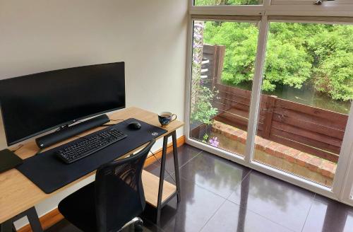 a computer desk with a keyboard and a monitor and a window at Riverside in York