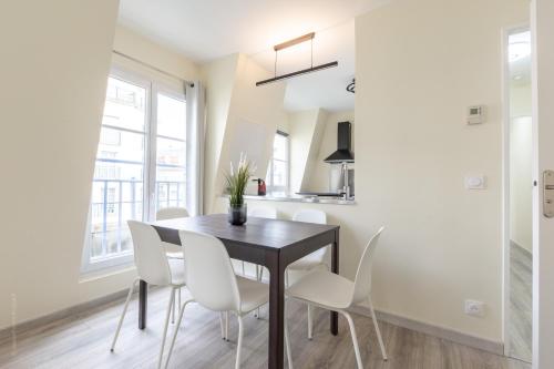a dining room with a black table and white chairs at Sweet Family Vacations - Fairytale Factory in Chessy