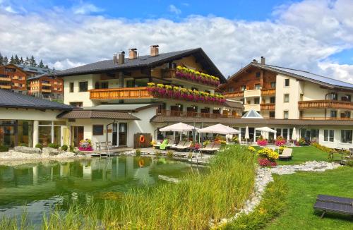 a hotel with a pond in front of a building at Alpinresort Schillerkopf in Bürserberg
