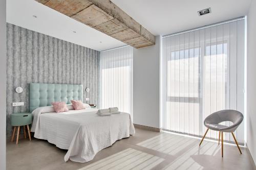 a bedroom with a bed with pink pillows and a chair at 9 NIDOS Céntrica Suites - Nuevo in Plasencia