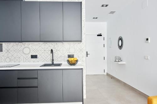 a kitchen with white cabinets and a sink at 9 NIDOS Céntrica Suites - Nuevo in Plasencia