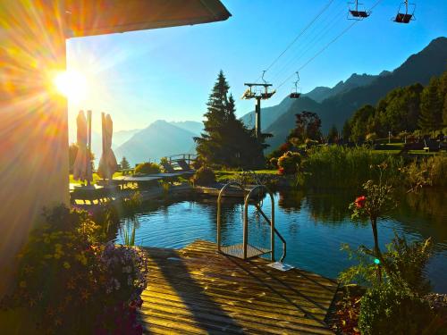 a view of a lake with the sun shining at Alpinresort Schillerkopf in Bürserberg