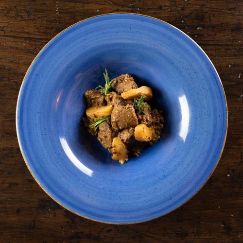 a blue plate with food on a wooden table at Locanda La Luna in Tirli
