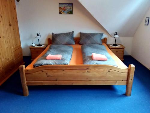 1 dormitorio con cama de madera y 2 almohadas rosas en Deichgraf, en Greetsiel