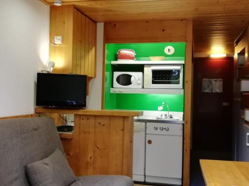 une petite cuisine avec un micro-ondes et une cuisinière dans l'établissement Appartement 5 personnes proche pistes à Arc 1800, village de Charmettoger - FR-1-411-209, à Arc 1800