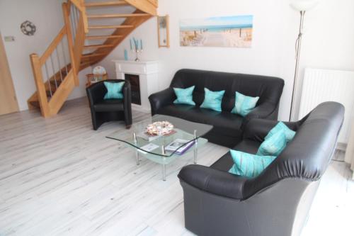 a living room with a black leather couch and a table at Villa Petra in Norddeich