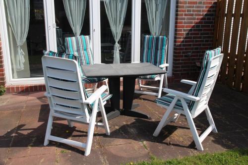 three chairs and a table in front of a house at Villa Petra in Norddeich