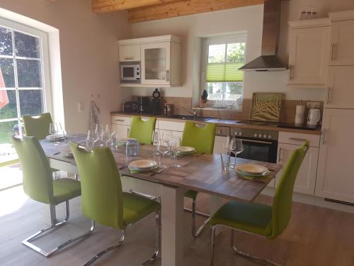 uma cozinha com uma mesa de madeira e cadeiras verdes em Steuerbord em Eilsum