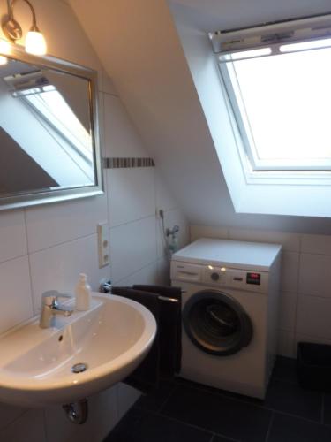 a bathroom with a sink and a washing machine at Grachtenperle in Greetsiel