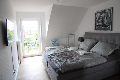 een slaapkamer met een bed en een glazen schuifdeur bij Deichblick 2 in Greetsiel