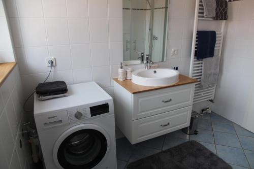 ein Badezimmer mit einer Waschmaschine und einem Waschbecken in der Unterkunft Deichblick 2 in Greetsiel