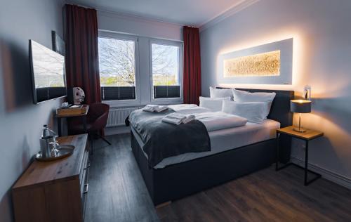 a bedroom with a bed and a desk and two windows at Hotel Boutique am Schloss in Schleswig