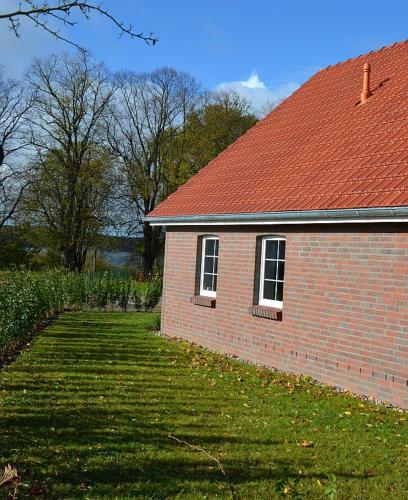 a brick house with a red roof and a grass yard at Storchennest in Warin