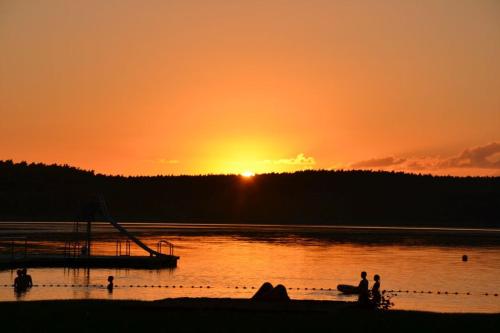 a sunset over a lake with people in the water at Storchennest in Warin