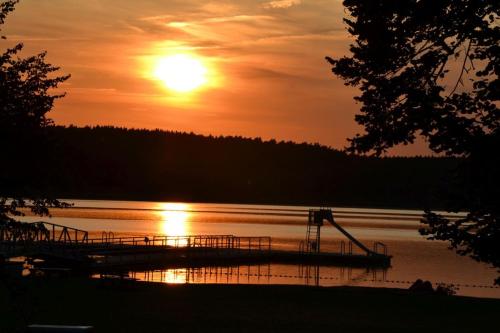 a dock on a lake with the sun setting at Storchennest in Warin