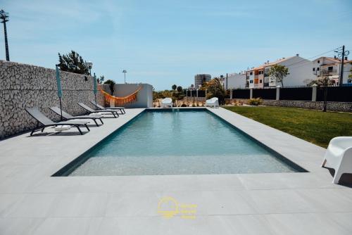a swimming pool with lounge chairs next to a wall at Yellow Sweet Home - Maria e Beatriz in Nazaré