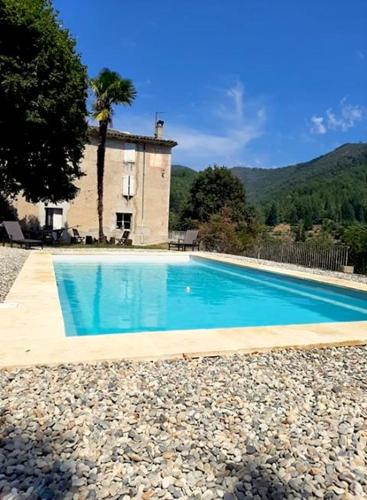 une grande piscine devant une maison dans l'établissement EcoVacances à la Ferme Le Pouget - Le Studio, à Saint-Jean-du-Gard