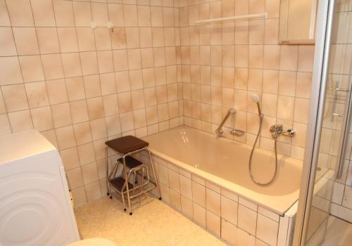 ein Badezimmer mit Badewanne und Dusche und einem Hocker in der Unterkunft Christel Zwischenahn in Bad Zwischenahn