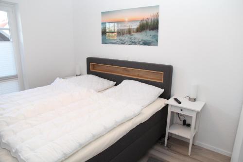 a bed in a bedroom with a picture on the wall at Zinnenhuus 1 in Greetsiel