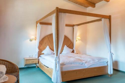 a bedroom with a canopy bed with white sheets at Ferienparadies Sabina Zirbel in Alpe di Siusi