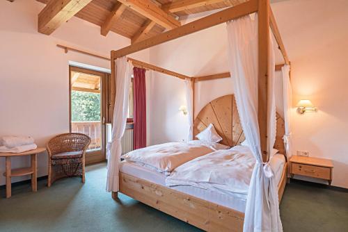 a bedroom with a canopy bed and a table and a window at Ferienparadies Sabina Zirbel in Alpe di Siusi