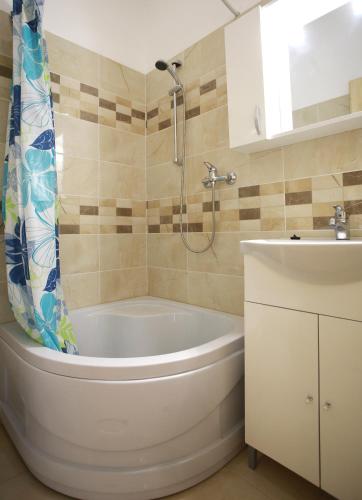 a bathroom with a tub and a shower and a sink at Centrál Panzió in Szentes