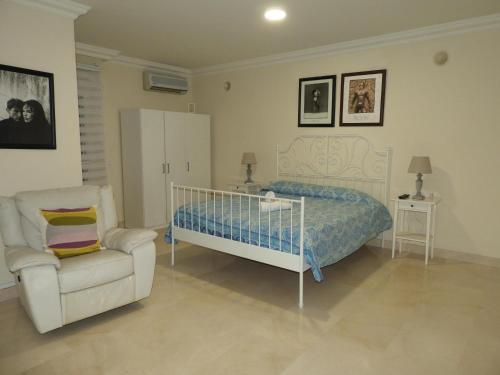 a bedroom with a bed and a white chair and a chair at Dream Villa in Adeje
