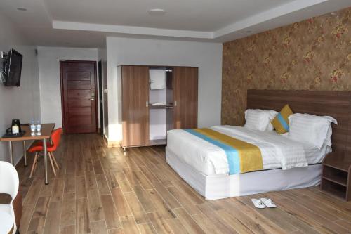 a hotel room with a bed and a desk and a table at Centric Hotel in Kigali