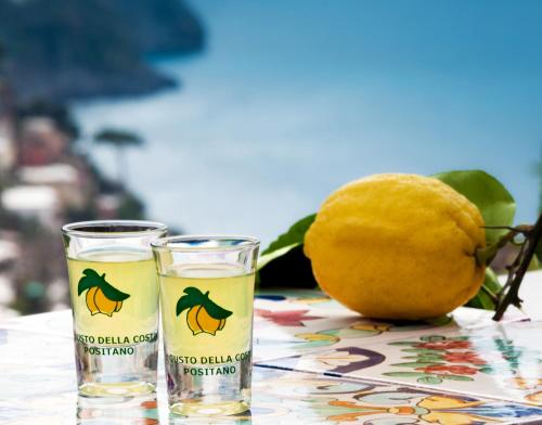 two glasses of yellow liquid next to an orange at Hotel Royal Positano in Positano