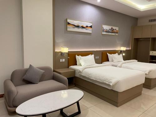 a hotel room with two beds and a couch and a table at Season Inn Hotel_Al Hail in Seeb