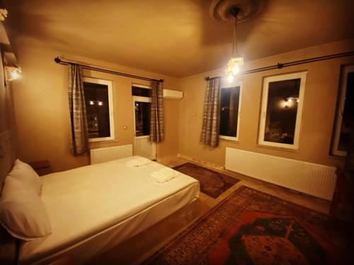 a bedroom with a white bed and two windows at Ala Stone House in Goreme