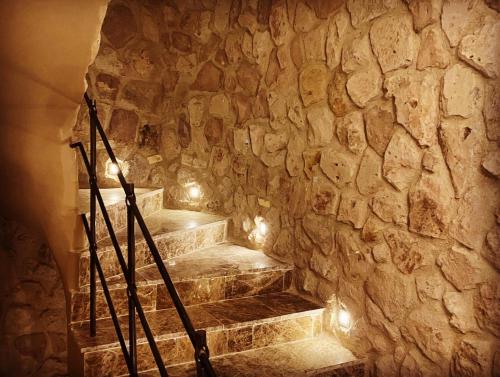 a stone wall with stairs in a room with lights at Ala Stone House in Goreme