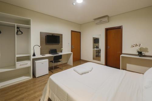 a bedroom with a bed and a desk with a computer at Hotel Itapema in Valinhos
