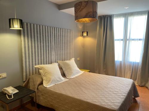 a bedroom with a bed with two pillows and a phone at Hotel Patilla Ciudad de Requena in Requena