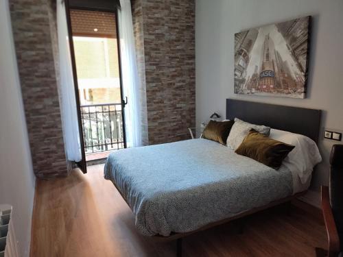 - une chambre avec un lit et un mur en briques dans l'établissement El Primero de Steven - Pegado a Playa de San Lorenzo, à Gijón